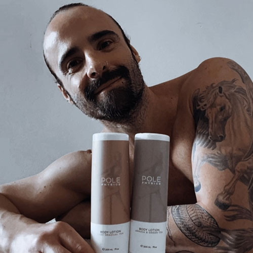 man with tattoos resting and grabbing two Pole Physics' lotions