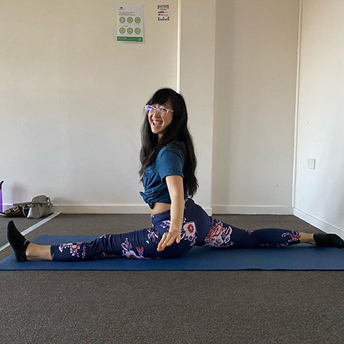 woman doing a split on a mat and smiling